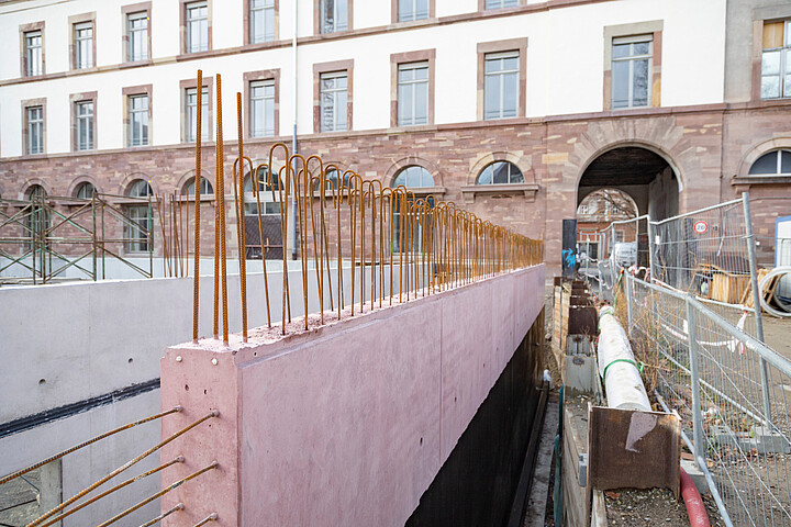 Pour une meilleure intégration à l’ensemble architectural, la nouvelle construction sera ceinturée d’un mur en béton rose teintée dans la masse. Crédit photo : Catherine Schröder