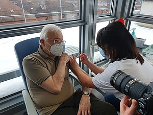 Jean-Marie Lehn, 81 ans, se prête au jeu des photos pendant qu'il se fait vacciner. Crédit : CHRU 