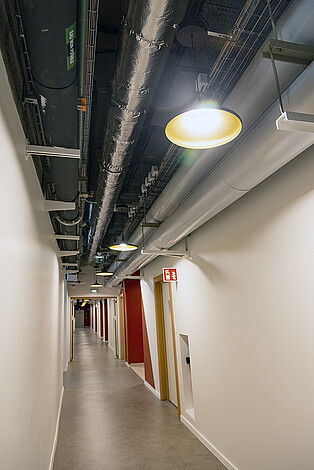 Un plenum technique visible (sans faux plafonds) avec les nouvelles lampes qui s’intègrent dans cet environnement de style industriel. 